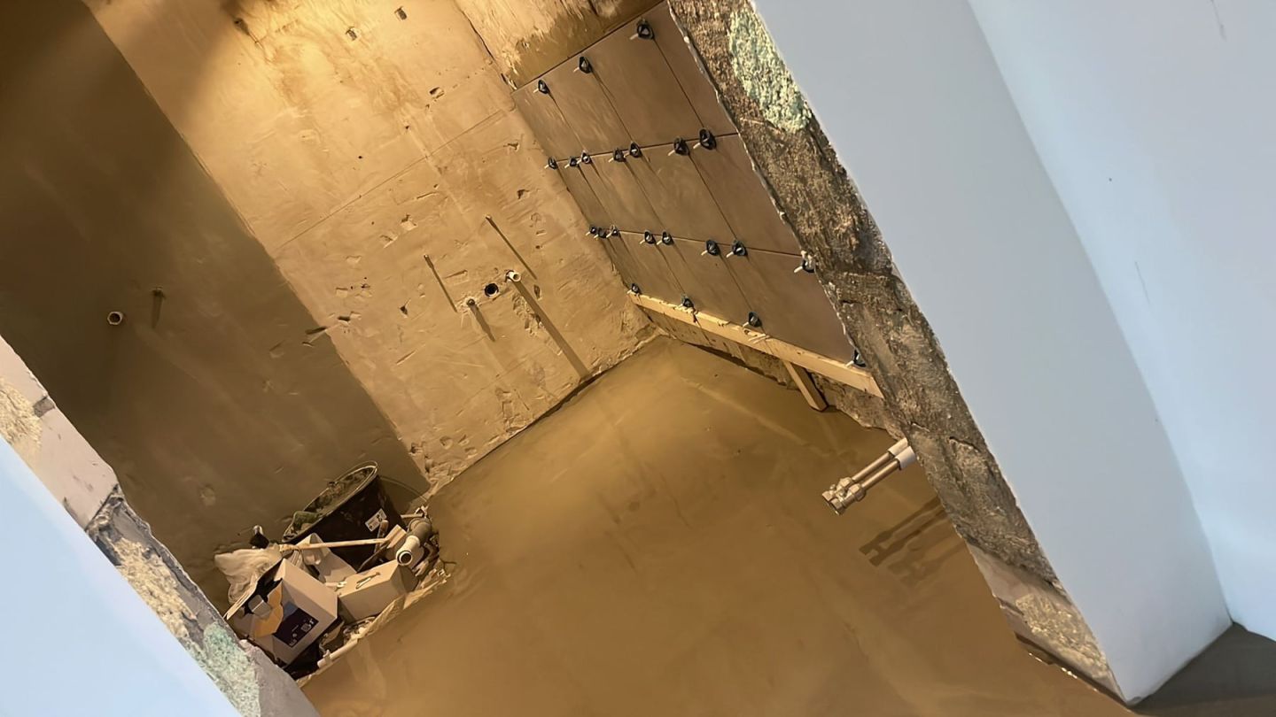 Raum mit neu gespachtelter Wand und daneben gesetzter Beplankung auf Ständerwerk, Boden frisch ausgeglichen